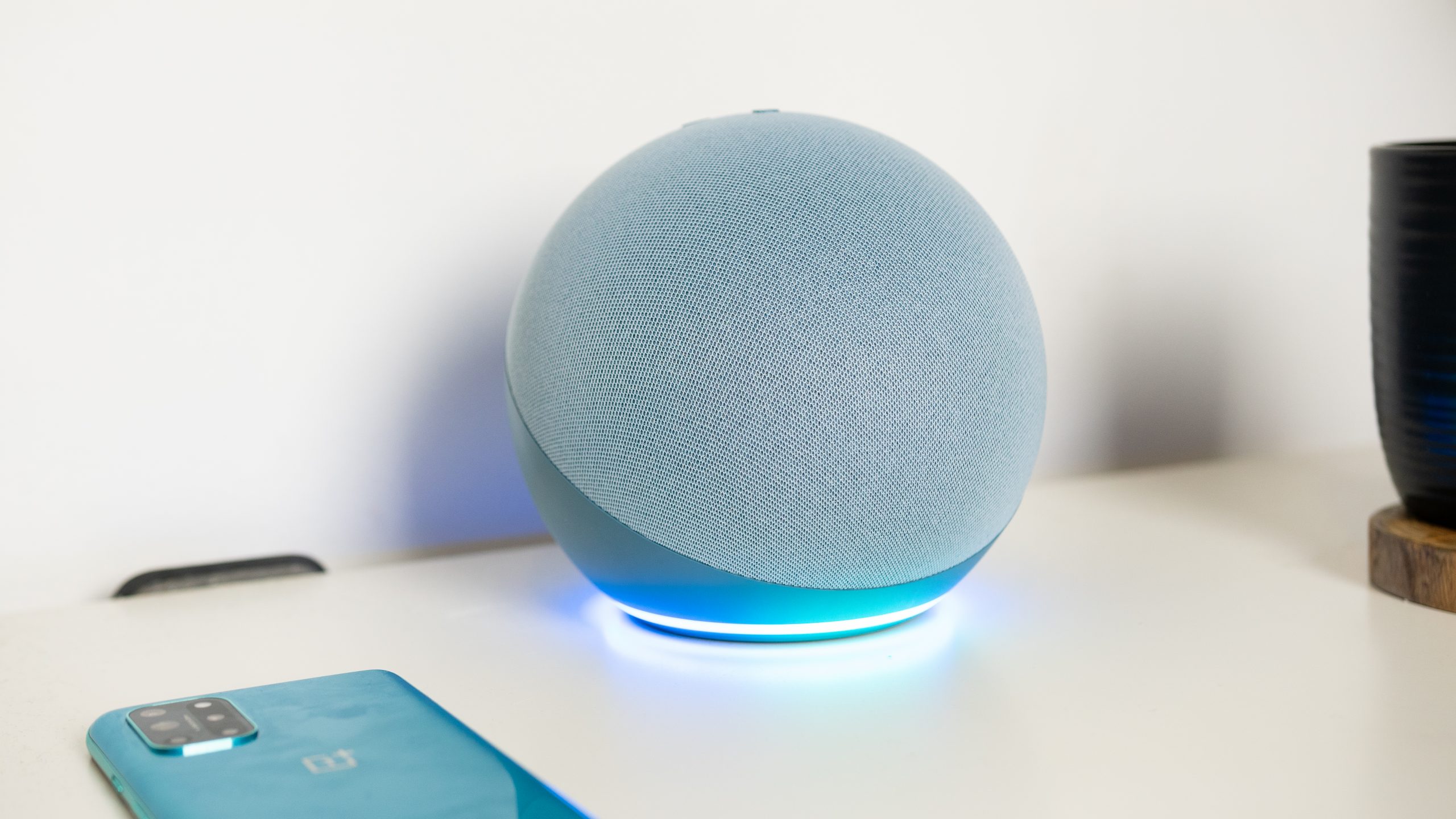 The Twilight blue Amazon Echo 4th gen with the LED light glowing blue on a white desk.