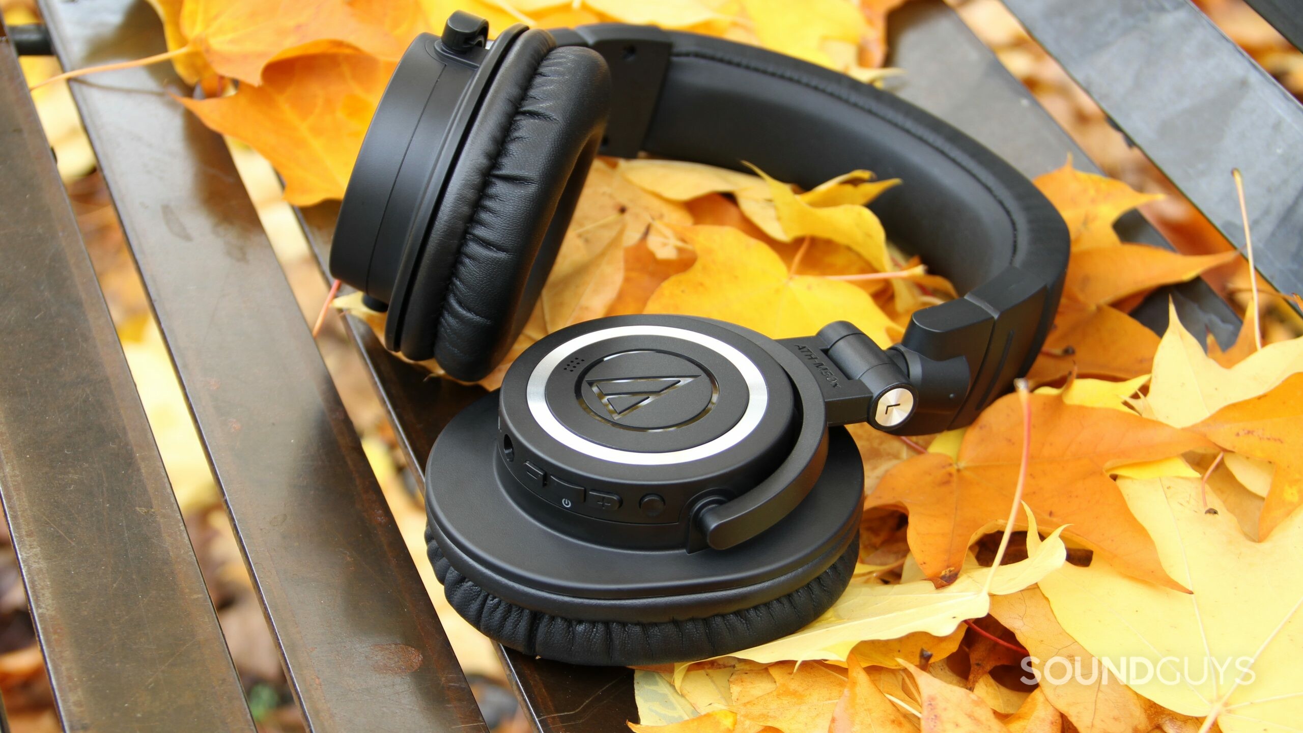 Audio-Technica ATH-M50xBT2 with one ear cup rotated laying flat on leaves.