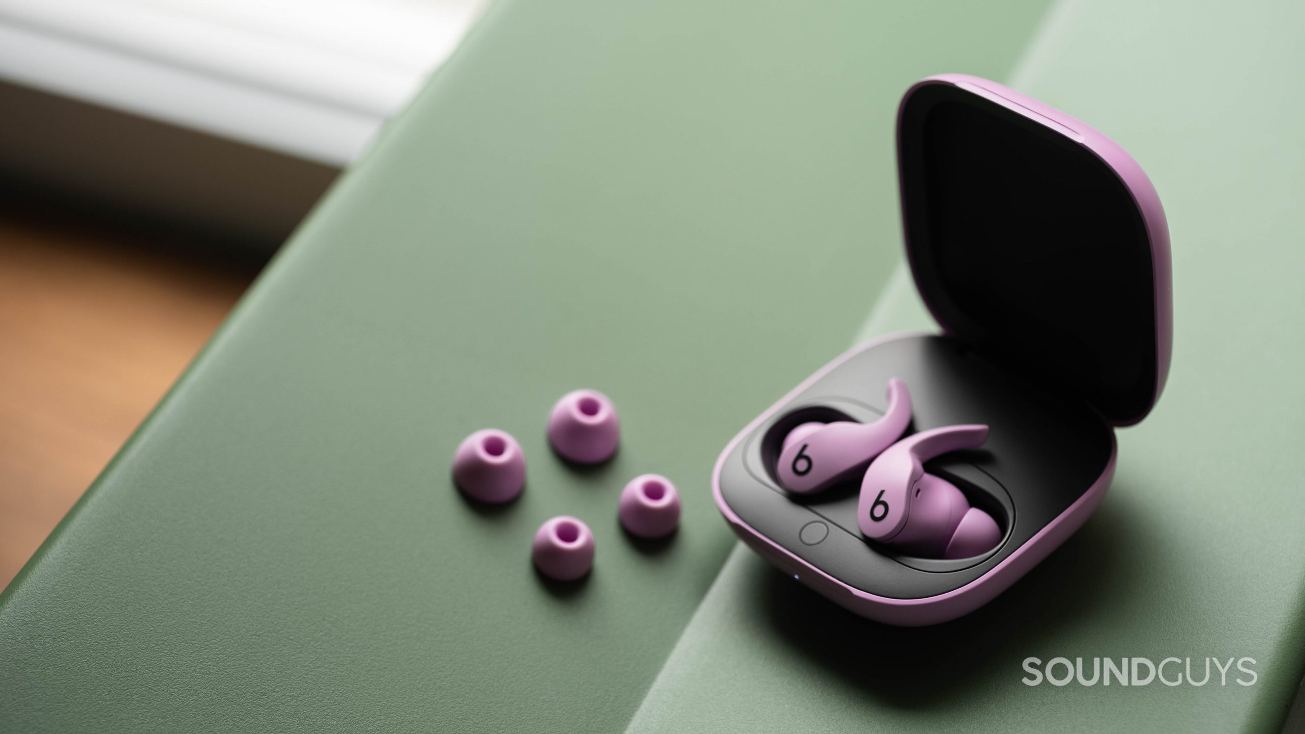 The Beats Fit Pro noise canceling true wireless earbuds in the open case and next to the two extra pairs of ear tips, all of which are in the purple variant.