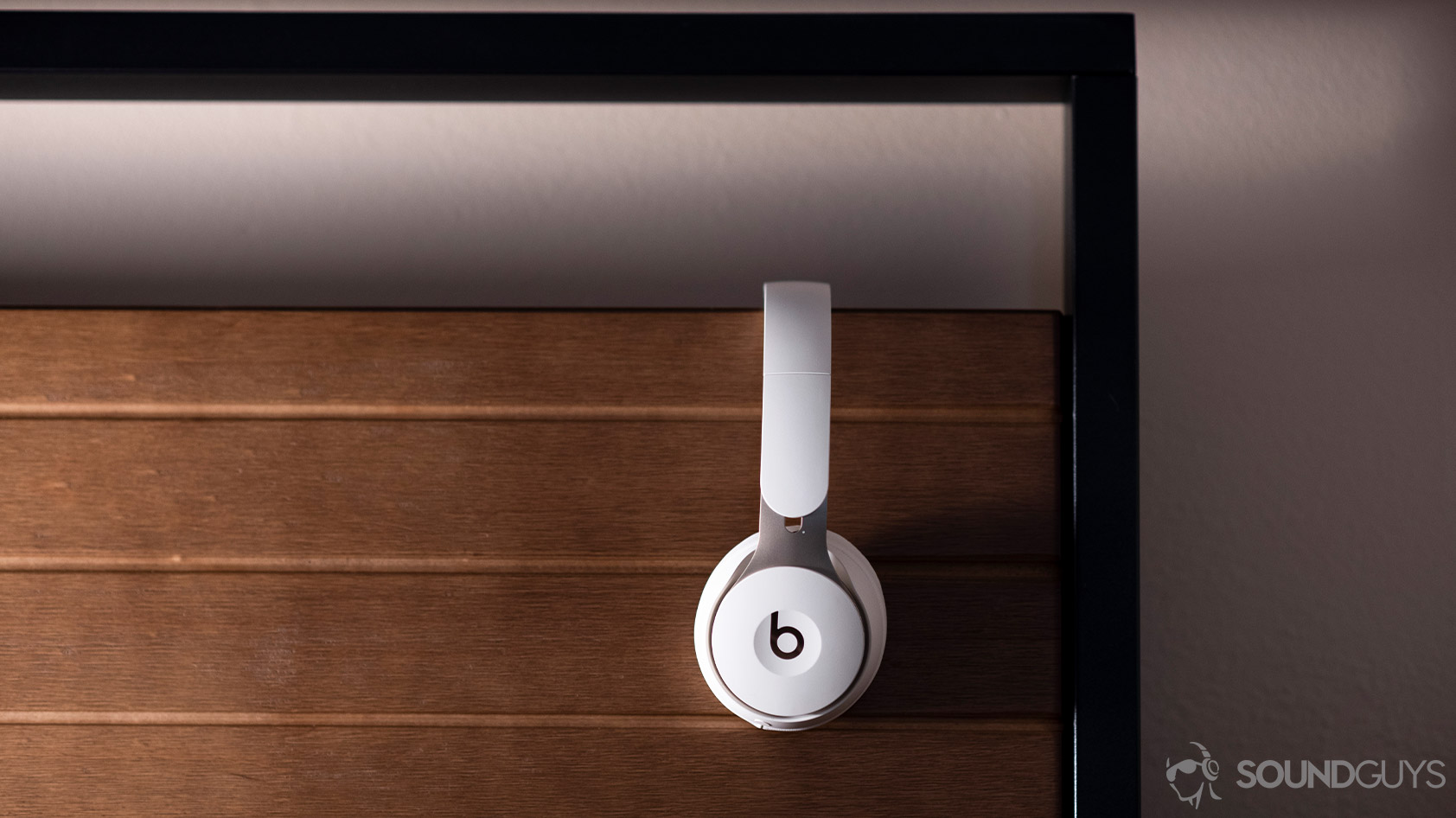 The Beats Solo Pro on-ear noise canceling headphones in profile against a wooden background.