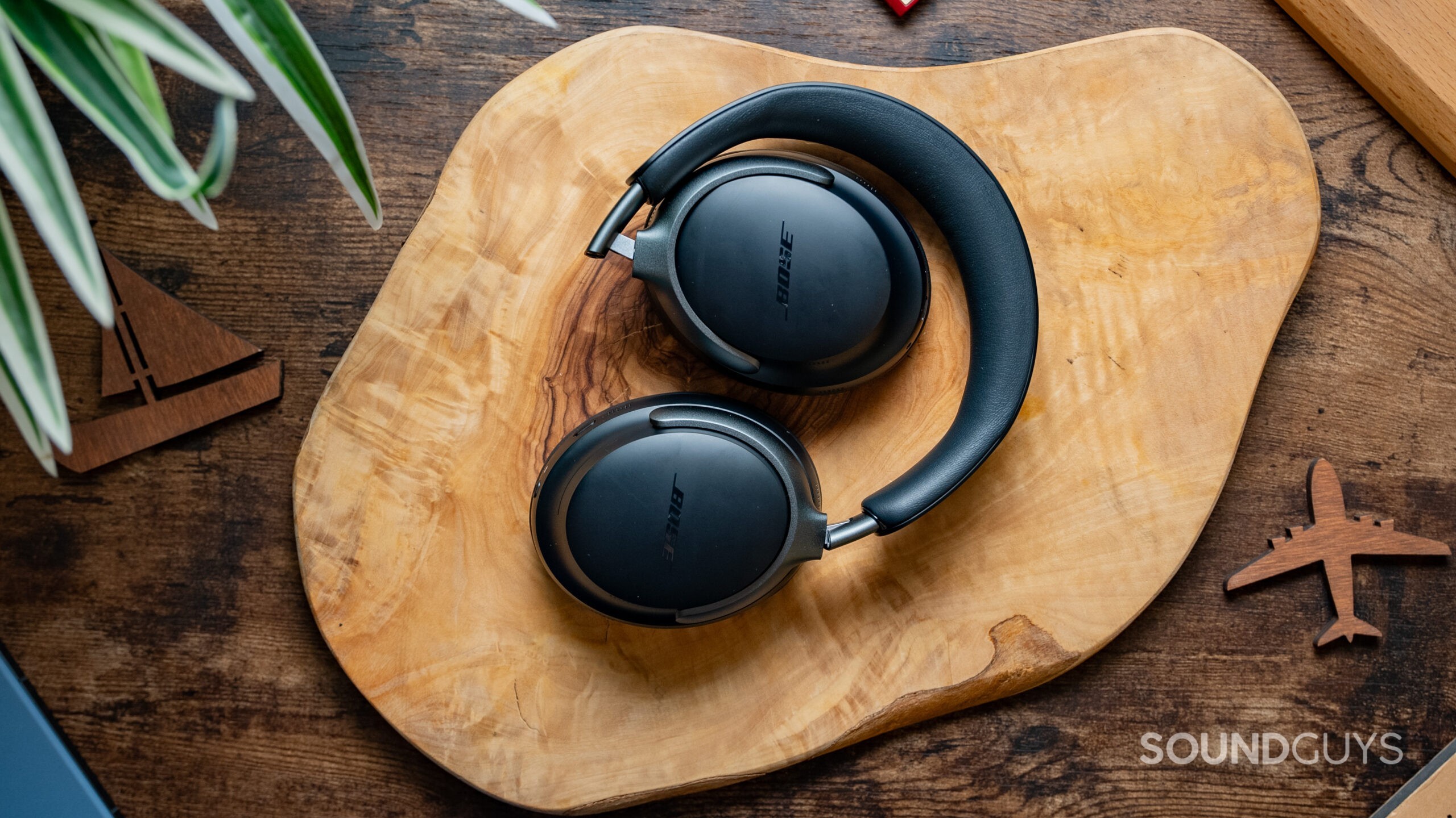 The Bose QuietComfort Ultra Headphones lying atop a wood slab.