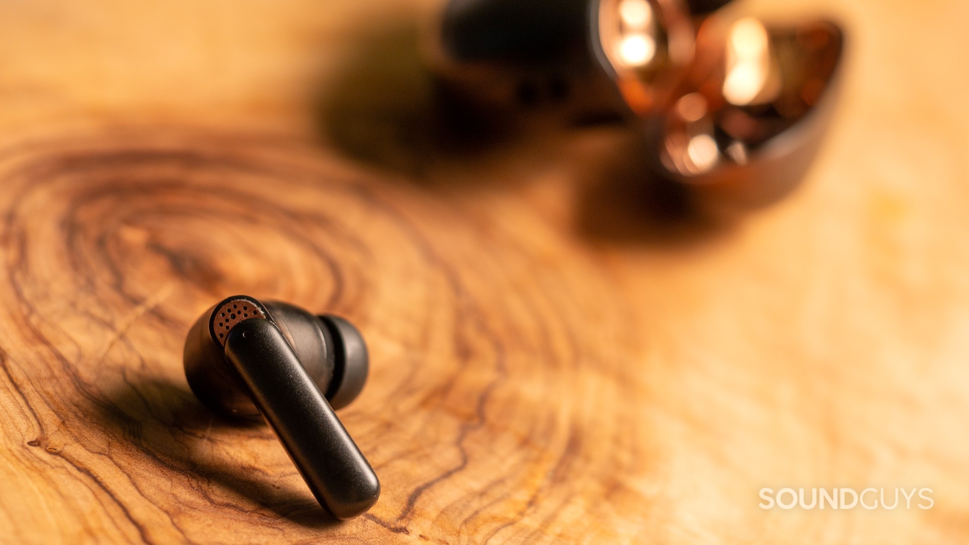 Creative Aurvana Ace 2 earbud on a wood table.