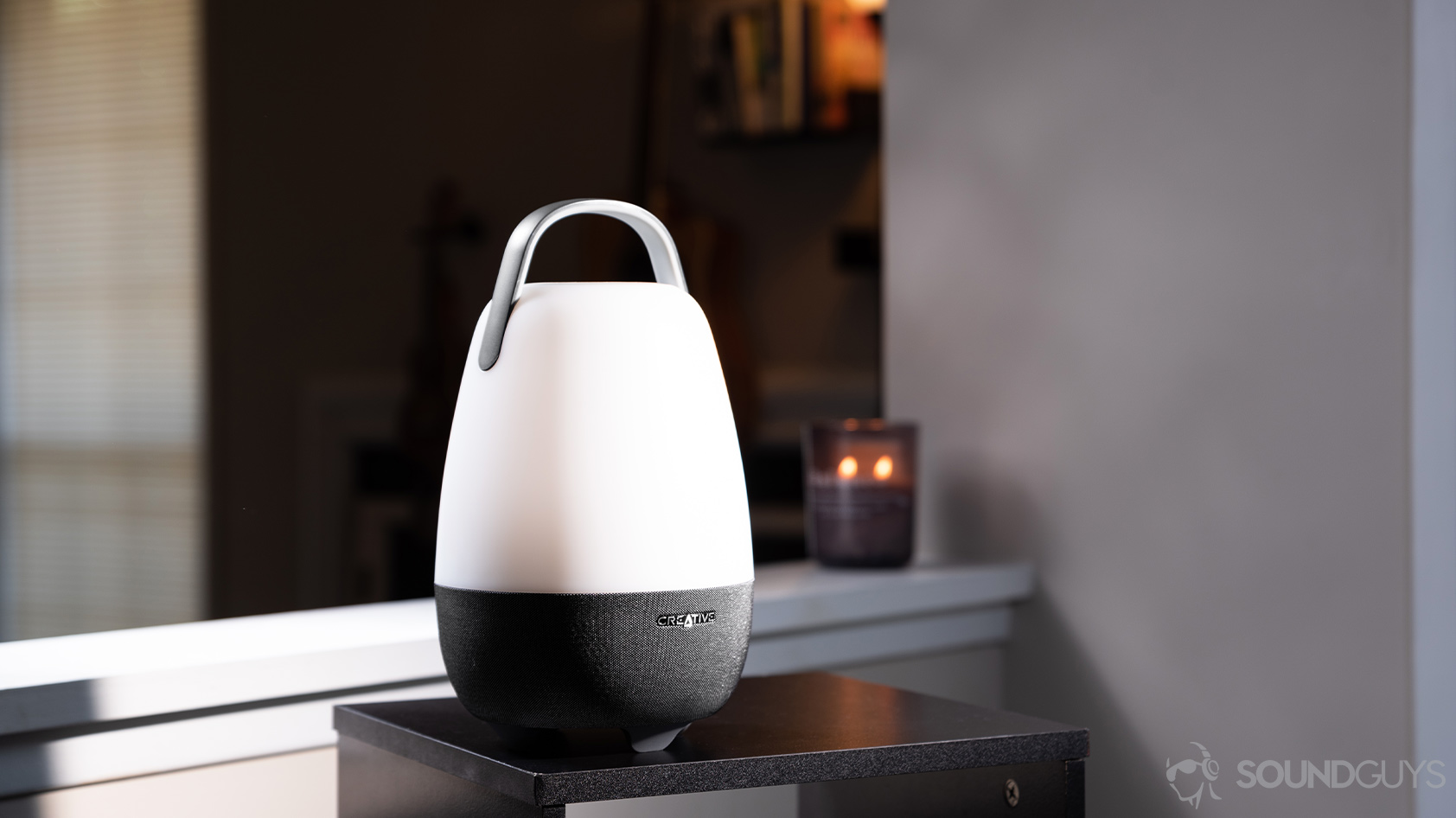 The speaker in a living room setting with a candle lit in the background.