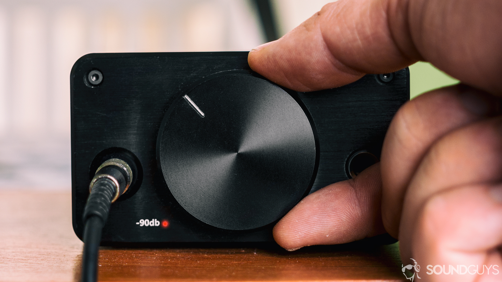 Different driver types: A photo of a hand turning up the knob of a headphone amplifier