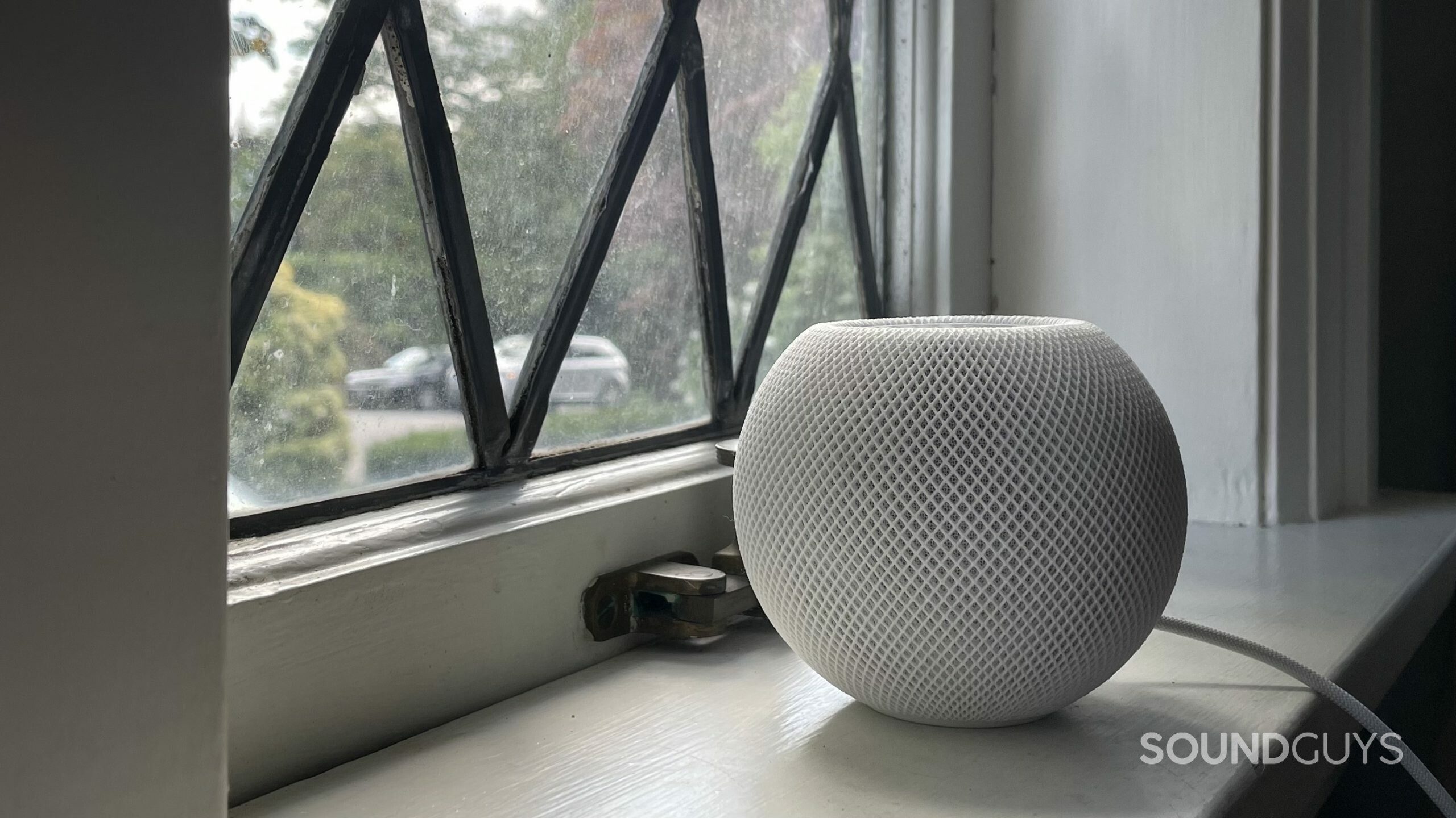 Apple HomePod mini resting on a windowsill.