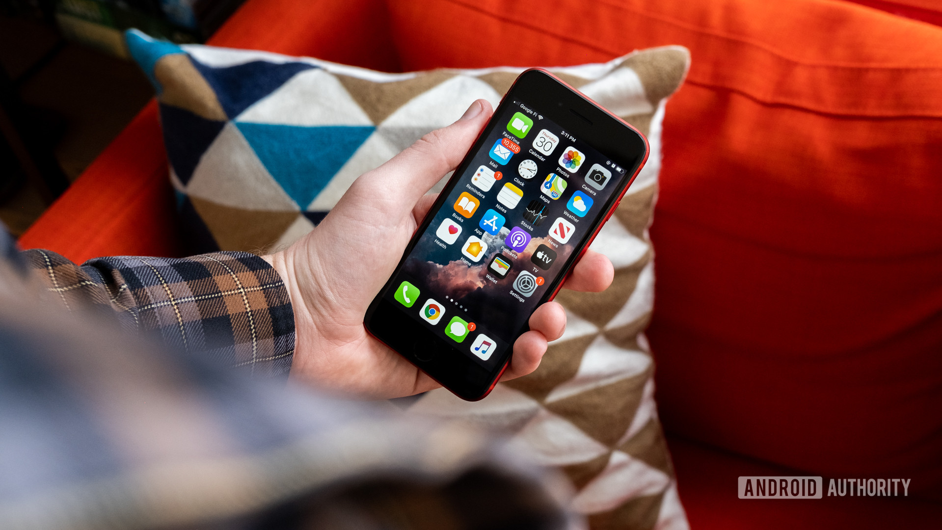 A photo of a man holding the Apple iPhone SE, with the screen on.