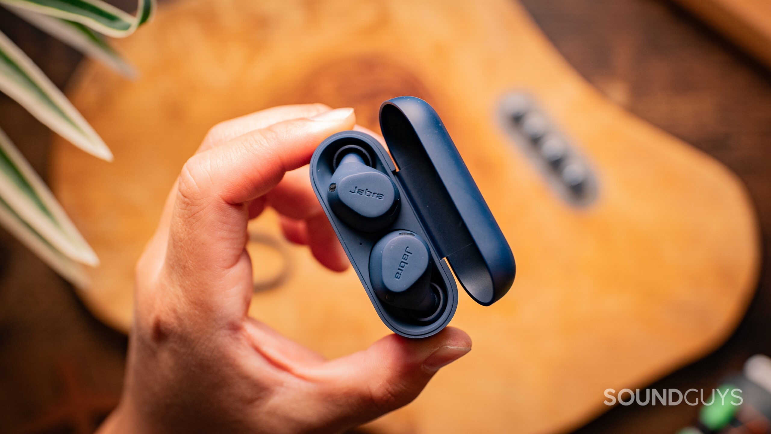 A hand holds the Jabra Elite 8 Active from a birdseye view showing the open case.