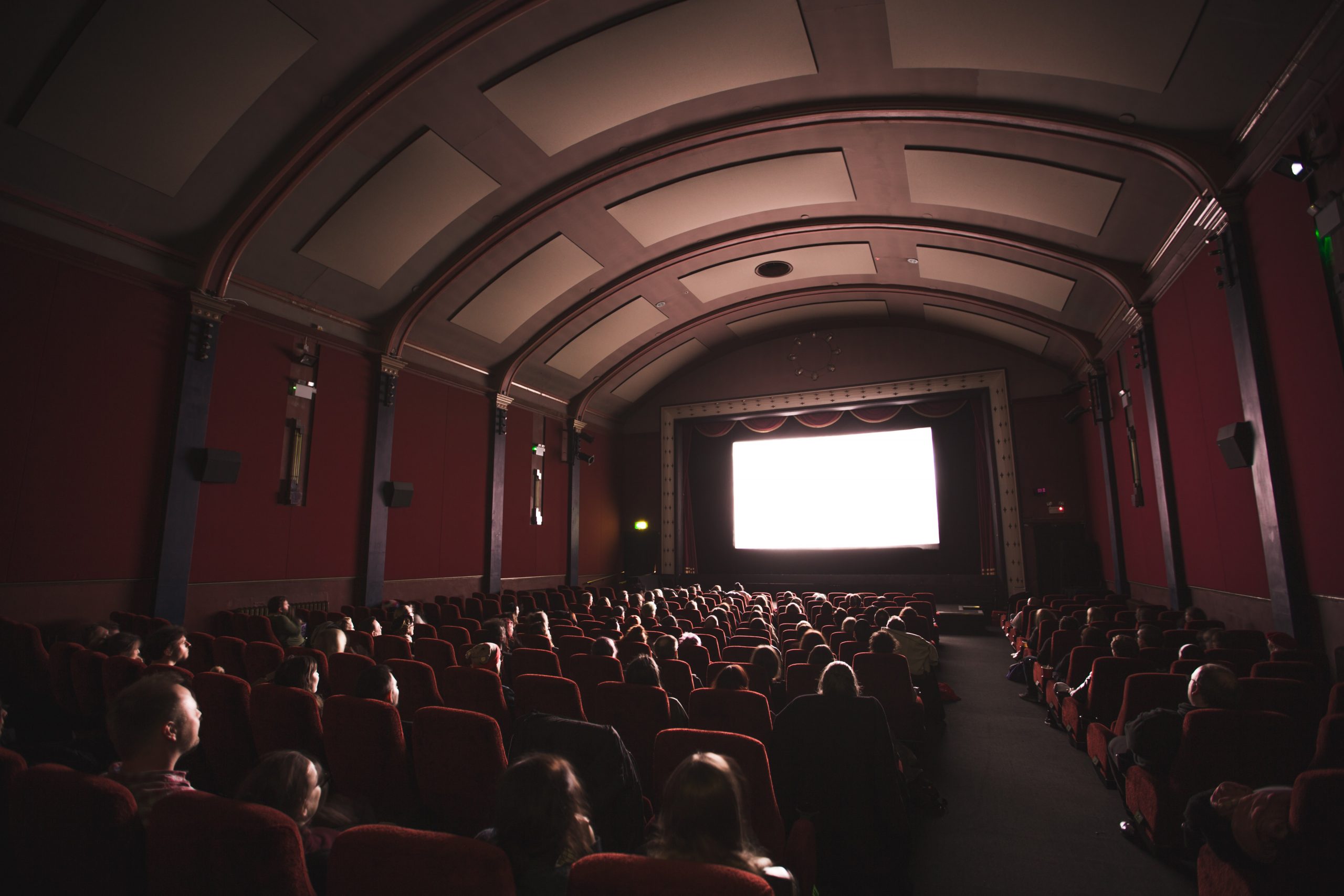 People watching a movie screen seen from back of the theater