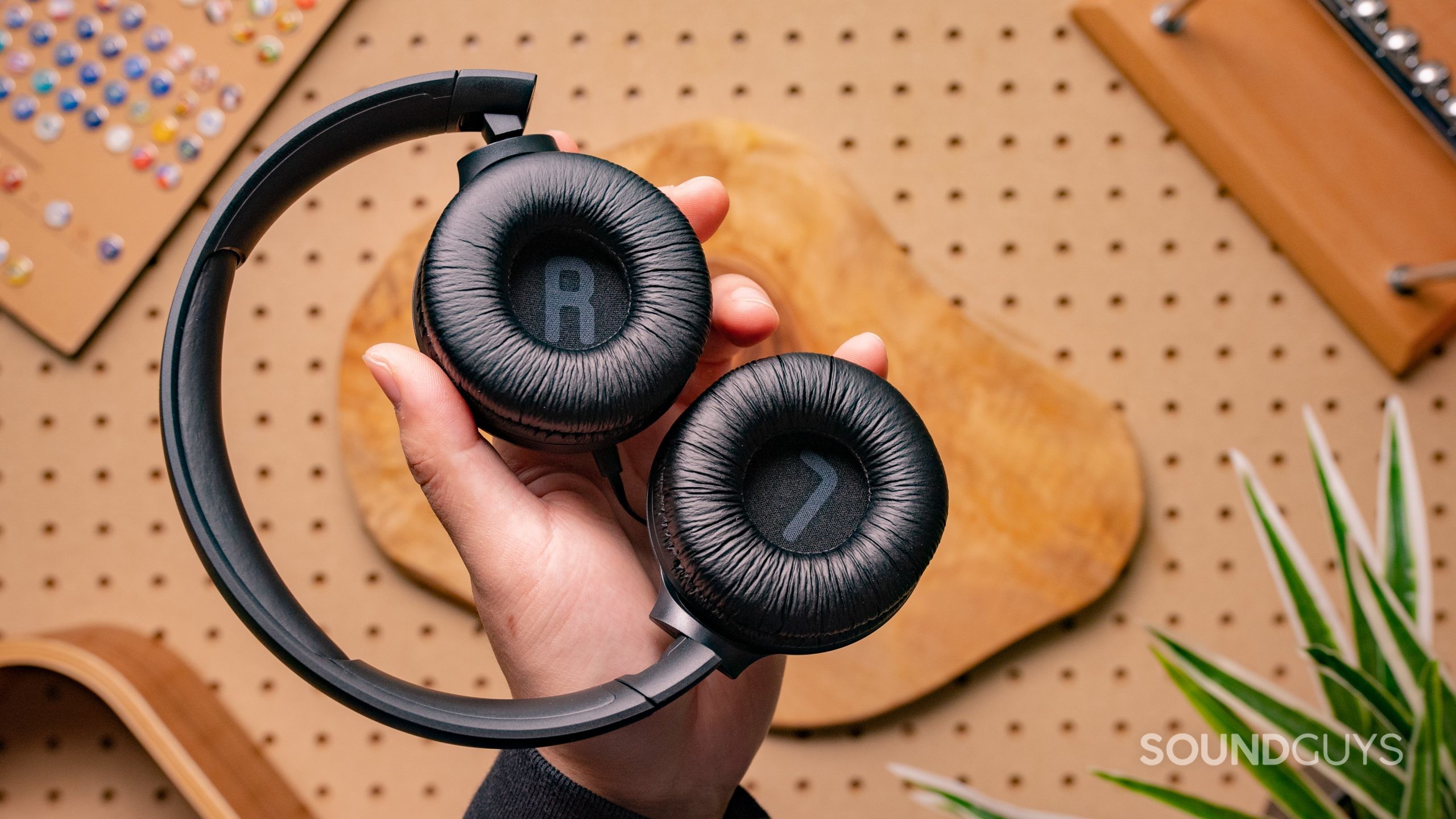 The JBL Tune 500 being held in someone's hands against a wooden backdrop.