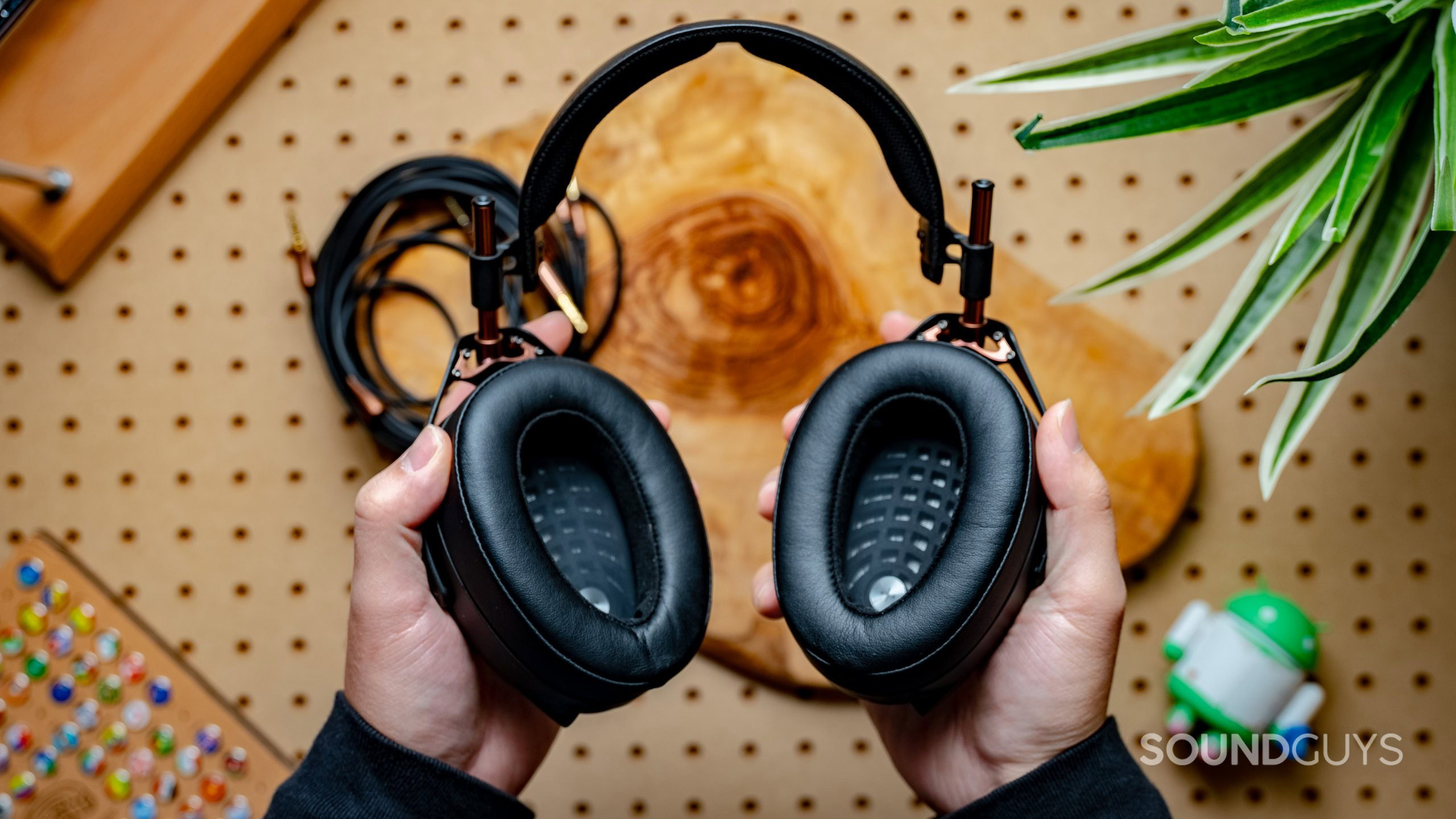 A photo of the Meze Audio Liric headphones, held in a man's hands, showing the drivers.