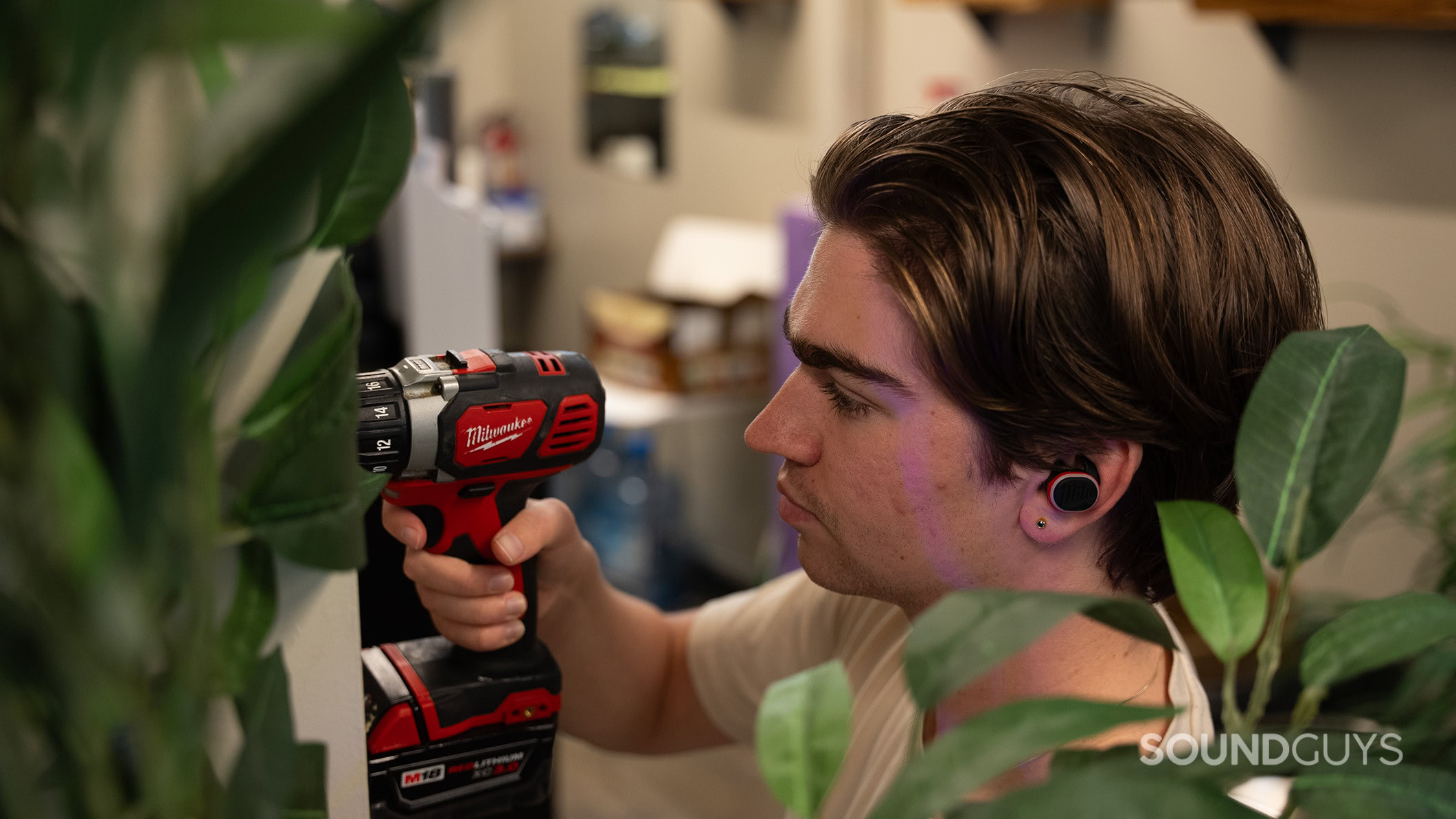 A man drills while wearing the Milwaukee earbuds. 