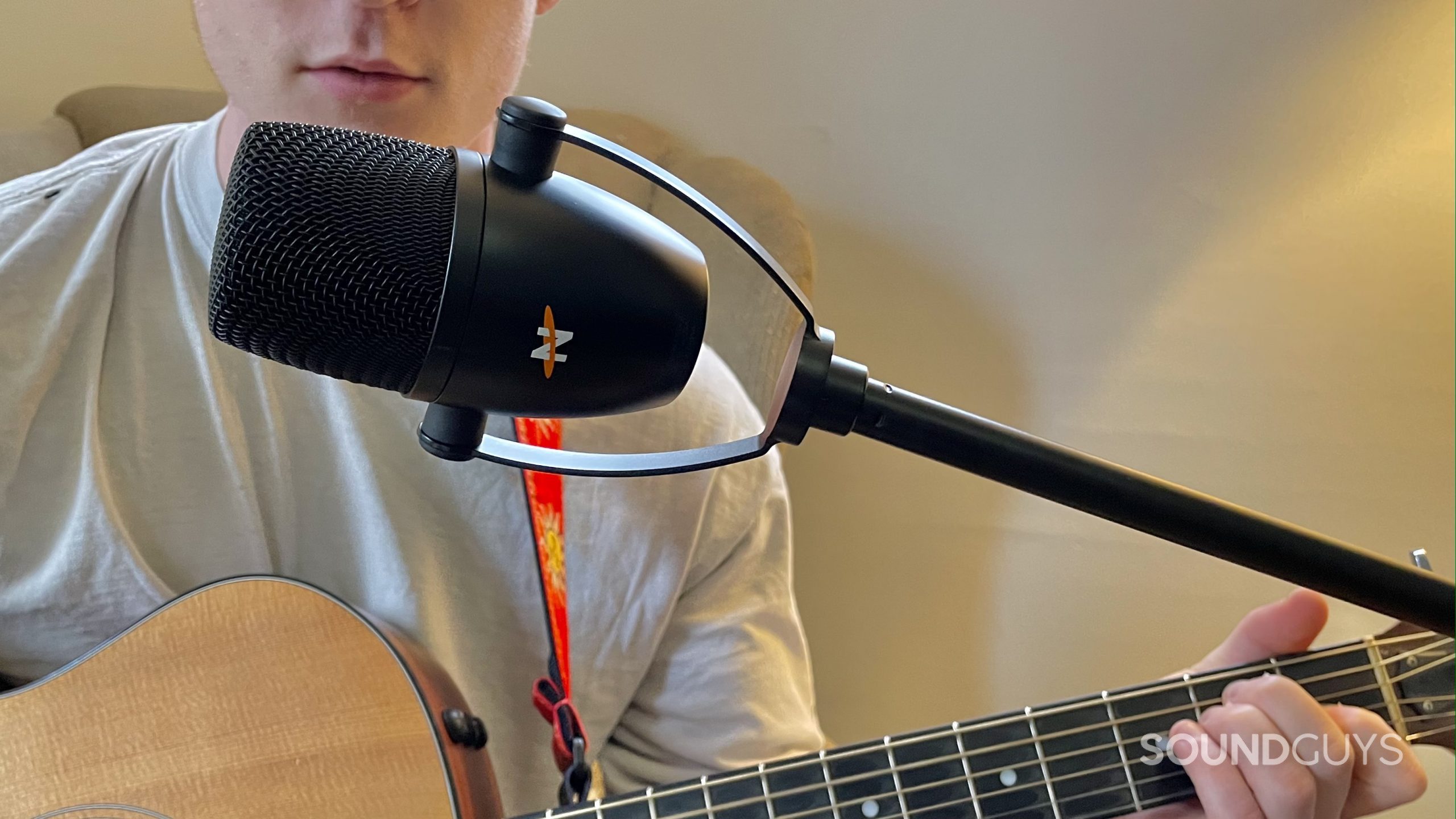 A man singing into the Neat Bumblebee II while playing a guitar.