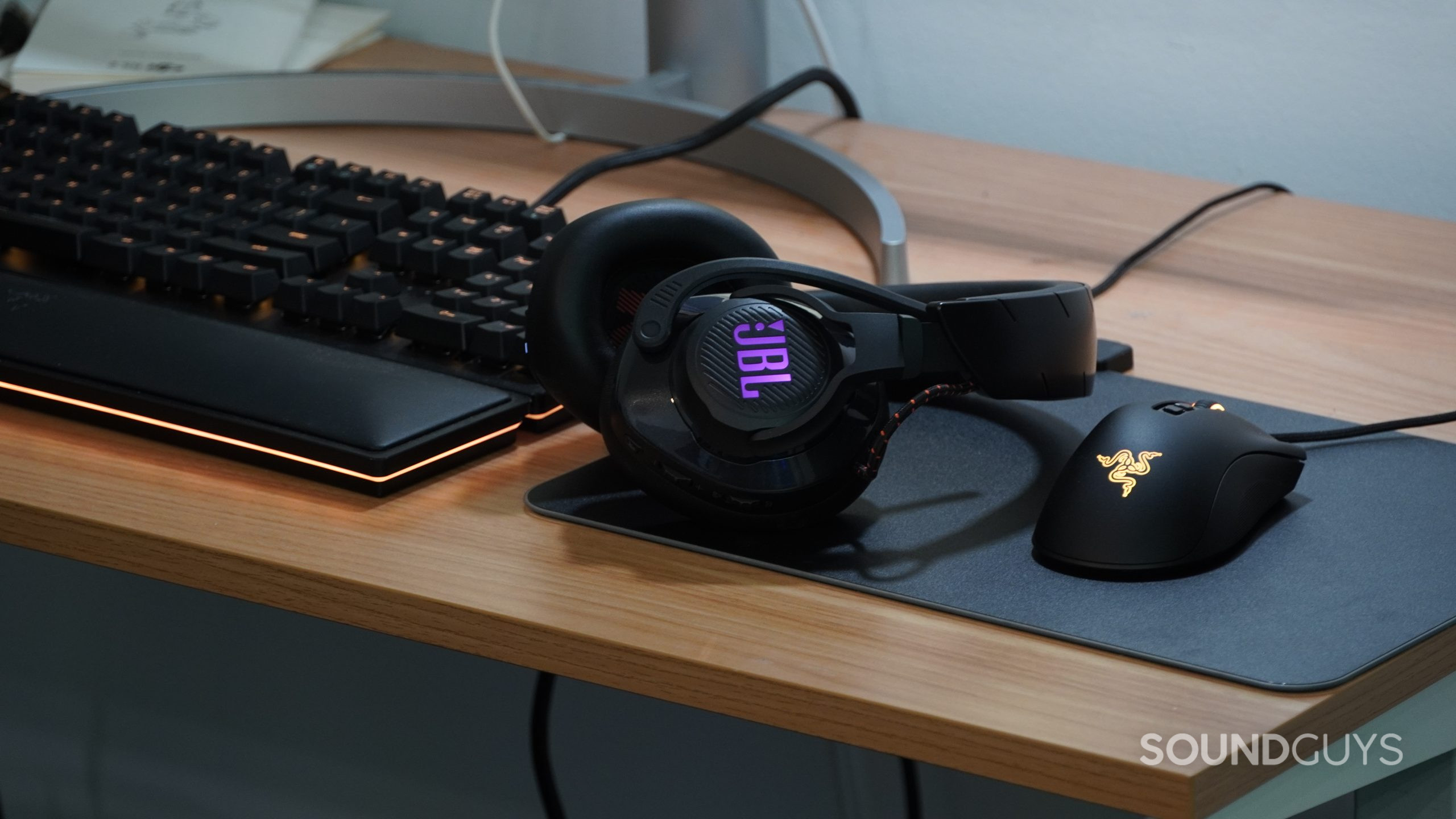 The JBL Quantum 600 on a desk next to some Razer peripherals