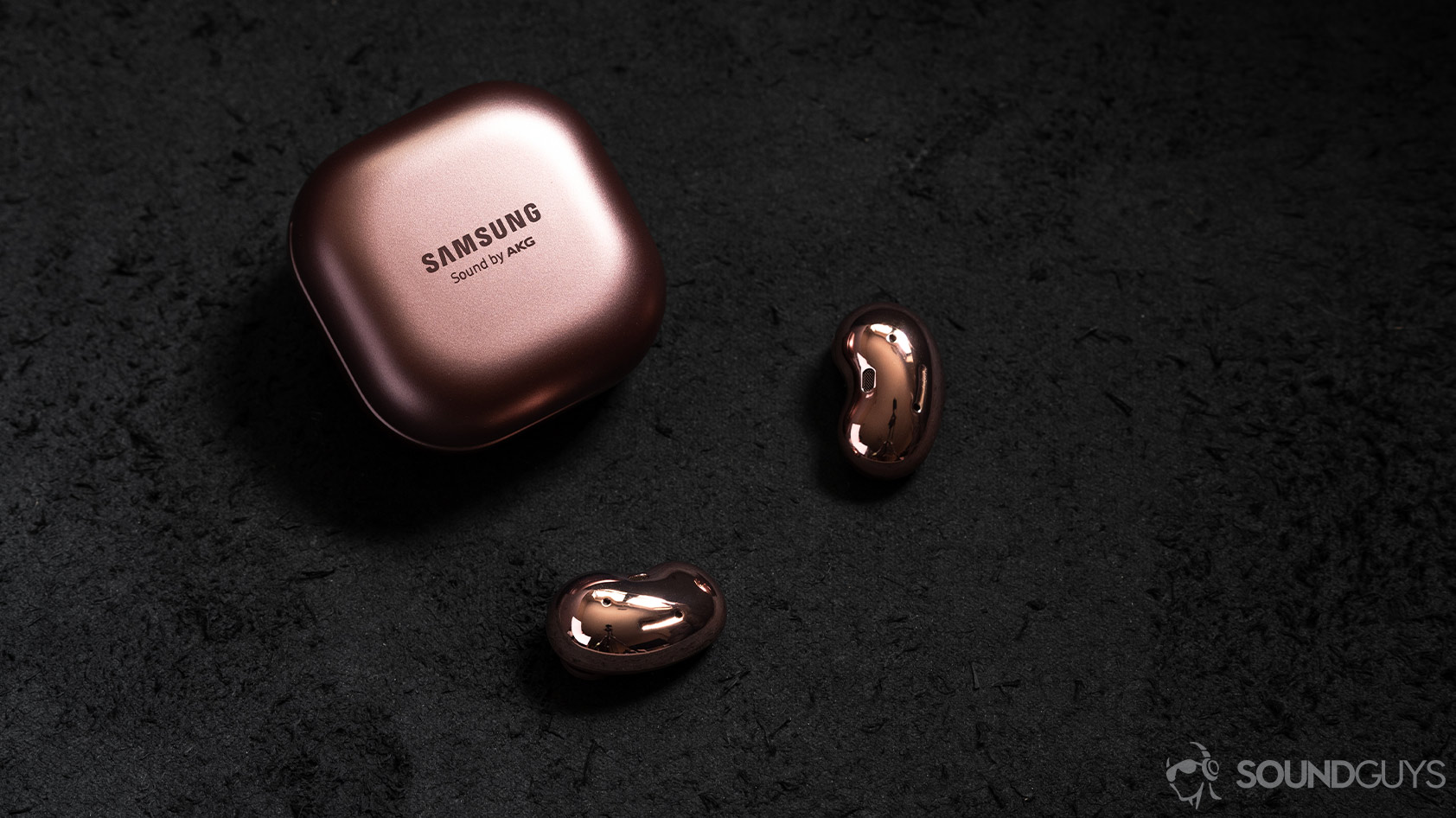 A picture of the Samsung Galaxy Buds Live noise canceling true wireless earbuds outside of the closed case and on a black surface.