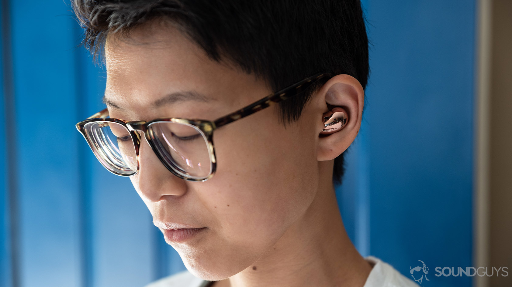 A close-up picture of a woman wearing the Samsung Galaxy Buds Live noise canceling true wireless earbuds in Mystic Bronze.