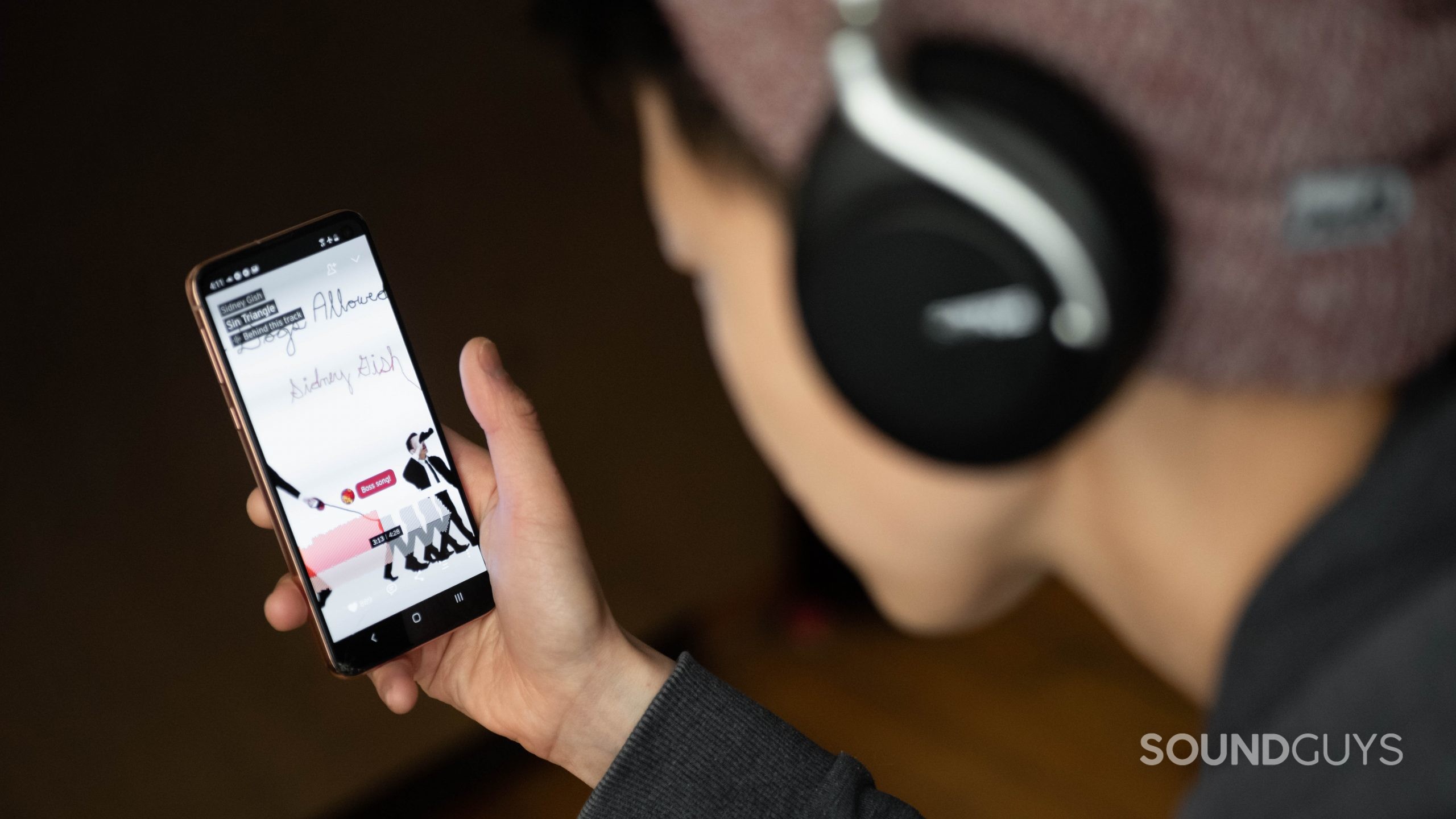 A woman listens to a song on SoundCloud from her smartphone.