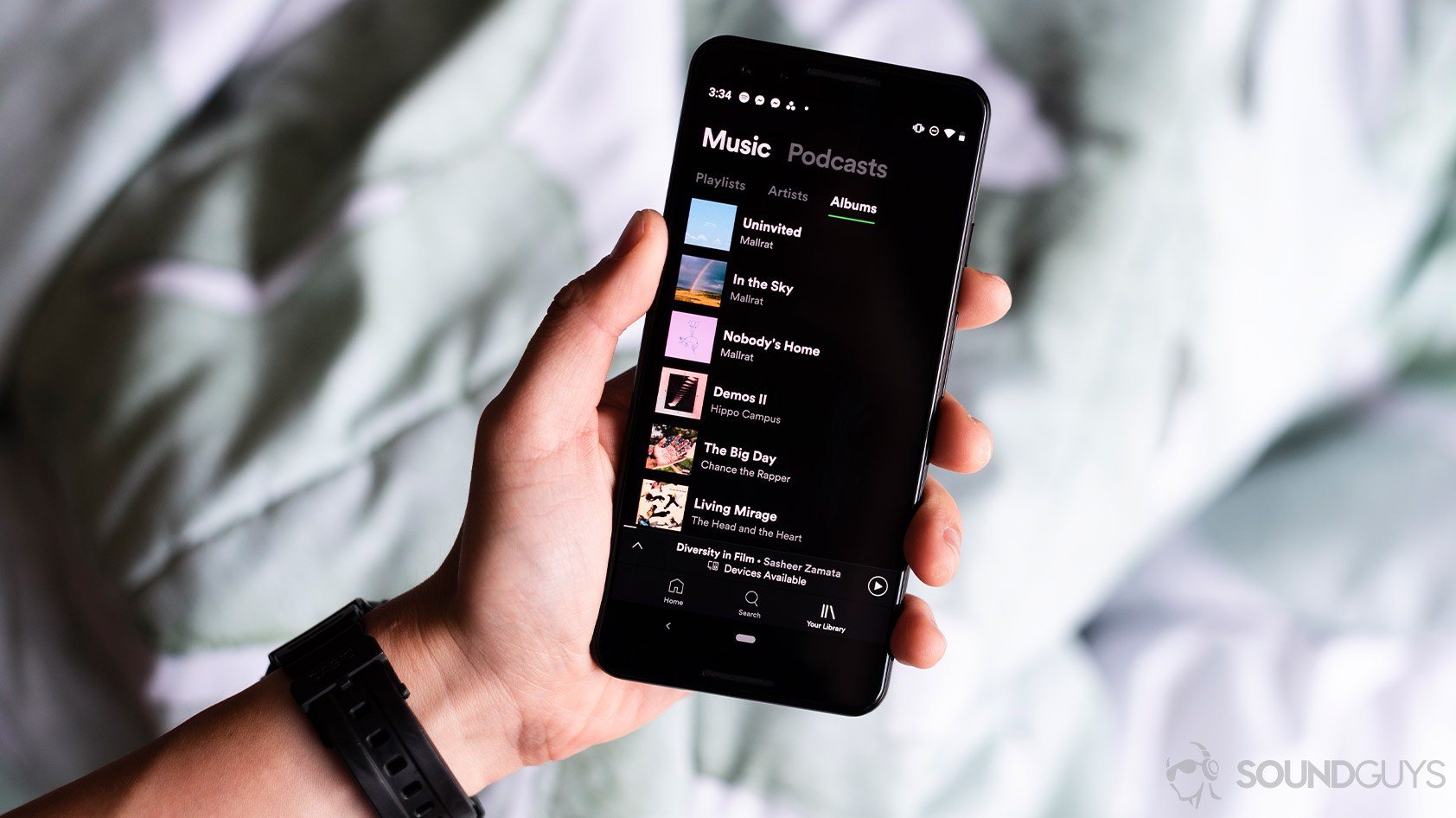 A woman holds a Google Pixel 3 phone with Spotify open on it.